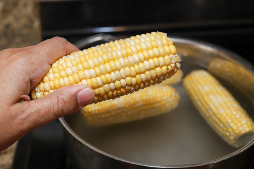 A African-American woman holding a corn on the cob in her hand