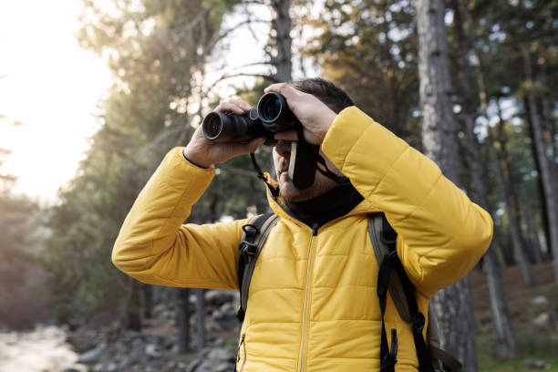 istock man in nature, looking through binoculars, in the forest 1369734977