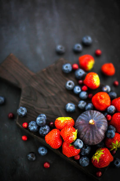 Fresh strawberries, blueberries and figs, on dark background, top view