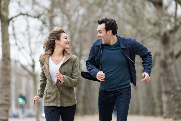 istock Fun couple smiling and laughing as they run towards camera 1369737774
