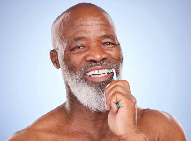 istock Studio portrait of a mature man brushing his teeth against a blue background 1369737948