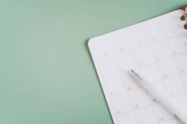 istock white pen on blank white planner  on green background, top view for timeline, schedule, routine work concept 1369741433