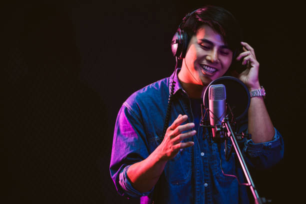 Asian male singer recording songs by using a studio microphone and pop shield on mic with passion in a music recording studio. Performance and show in the music business. Focus on male face Asian male singer recording songs by using a studio microphone and pop shield on mic with passion in a music recording studio. Performance and show in the music business. Focus on male face musician stock pictures, royalty-free photos & images