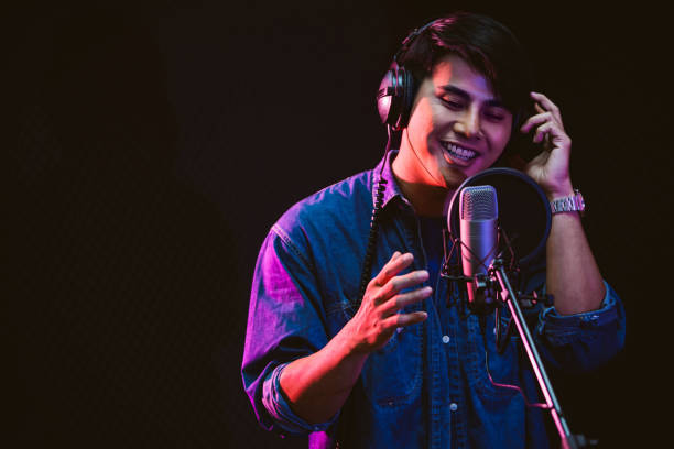 asian male singer recording songs by using a studio microphone and pop shield on mic with passion in a music recording studio. performance and show in the music business. focus on male face - músico imagens e fotografias de stock