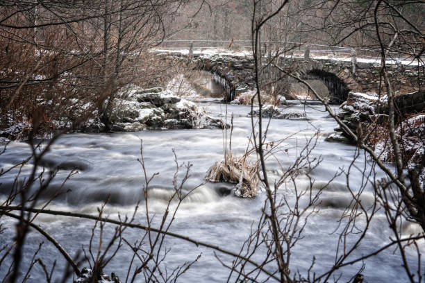 Snow and river flow on an old stone bridge