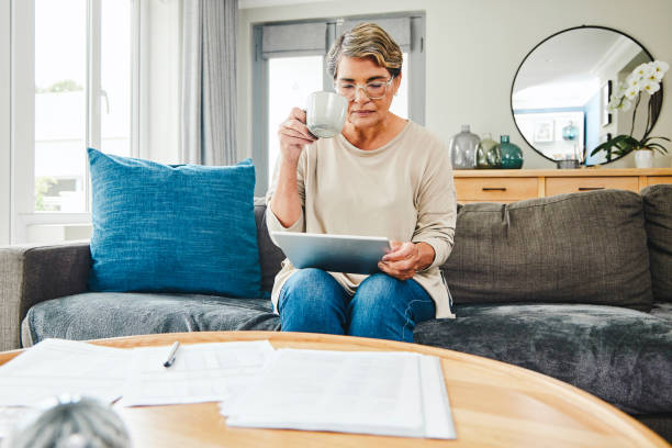 istock Shot of a mature woman using a digital tablet while going through paperwork at home 1369745007