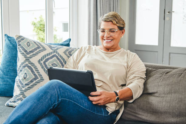 istock Shot of a mature woman using a digital tablet while relaxing at home 1369745062