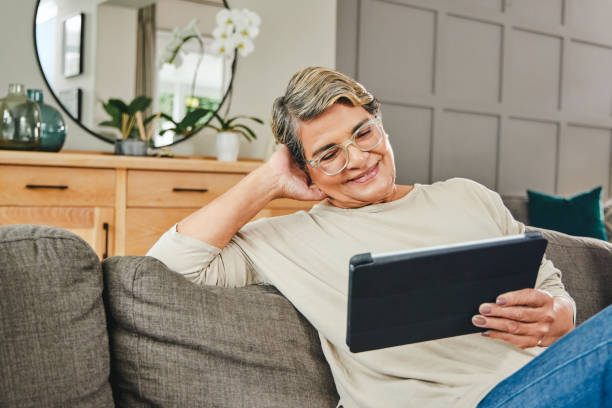 istock Shot of a mature woman using a digital tablet while relaxing at home 1369745079