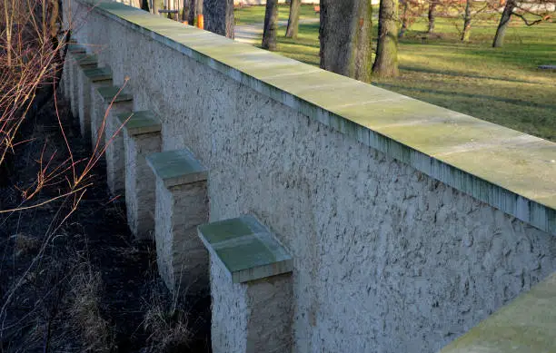 The wall of the garden reinforced on the back with brick pillars. Supports such a long wall and increases stability in wind and frost movements of the unstable subsoil.  protrude, protrusion, subsoil