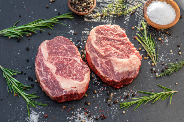 istock Raw Ribeye steaks with salt and herbs on grey board. Top view. 1369747727