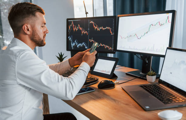 istock Graphs and diagrams. Young businessman in formal clothes is in office with multiple screens 1369747855