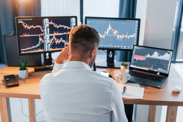 istock Hard working. Young businessman in formal clothes is in office with multiple screens 1369748745