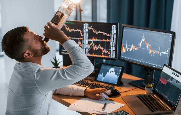 istock With alcohol. Young businessman in formal clothes is in office with multiple screens 1369748845