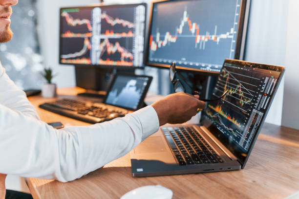 istock Analyzing information. Young businessman in formal clothes is in office with multiple screens 1369748997