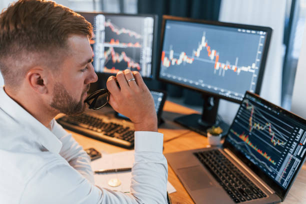istock Analyzing information. Young businessman in formal clothes is in office with multiple screens 1369748999