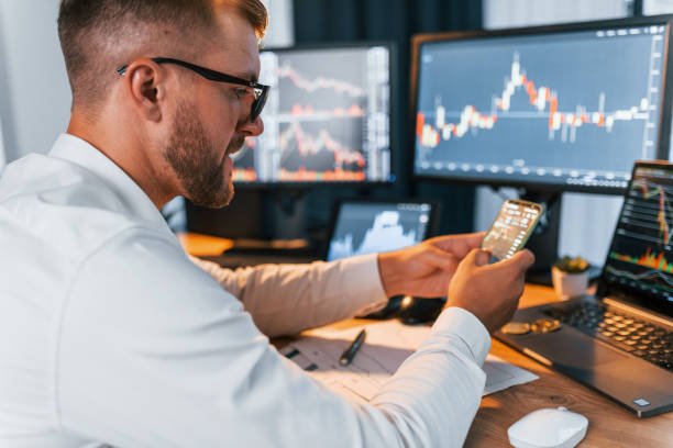 istock Many monitors. Young businessman in formal clothes is in office with multiple screens 1369749843