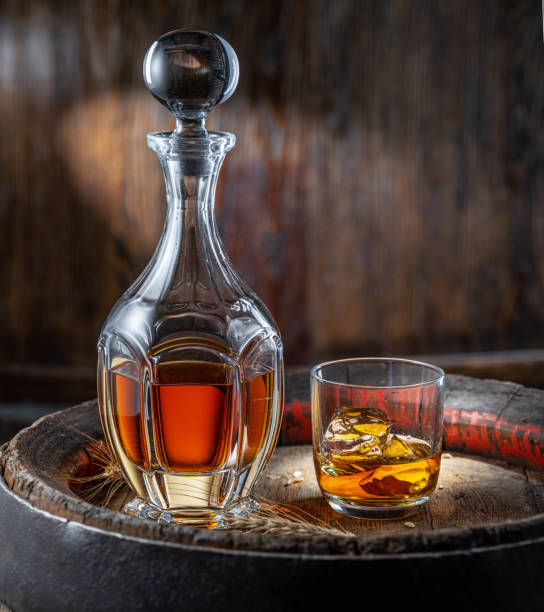 caraffa di whisky e bicchiere di whisky su vecchia botte di legno sullo sfondo scuro. - gin decanter whisky bottle foto e immagini stock