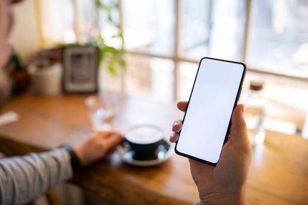 Shot of young man using smart phone and having coffee. Shot of young unrecognisable man using smart phone and having coffee. blank screen stock pictures, royalty-free photos & images