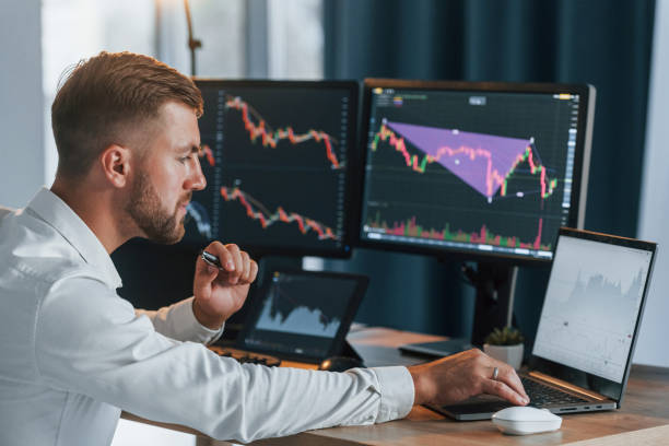 istock Successful young businessman in formal clothes is in office with multiple screens 1369750764