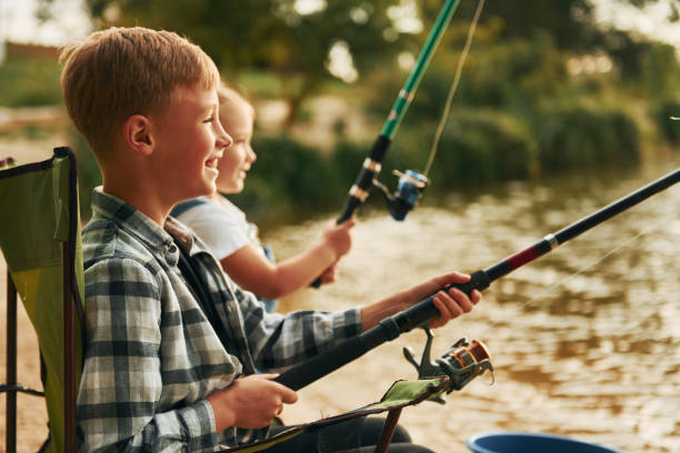 istock Medium sized lake. Boy with his sister in on fishion outdoors at summertime together 1369751068