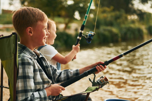 istock Medium sized lake. Boy with his sister in on fishion outdoors at summertime together 1369751081