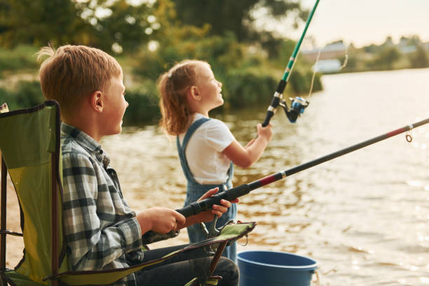 istock Medium sized lake. Boy with his sister in on fishion outdoors at summertime together 1369751090