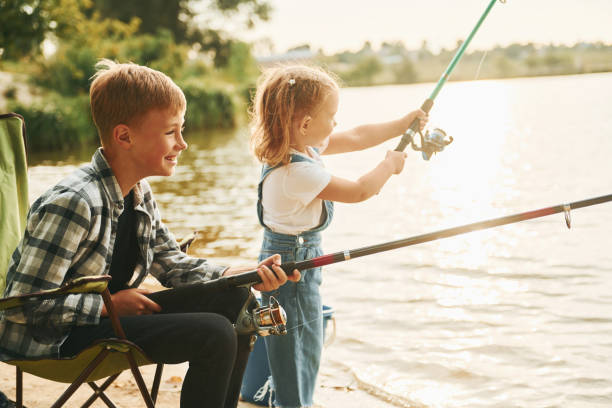 istock Medium sized lake. Boy with his sister in on fishion outdoors at summertime together 1369751132