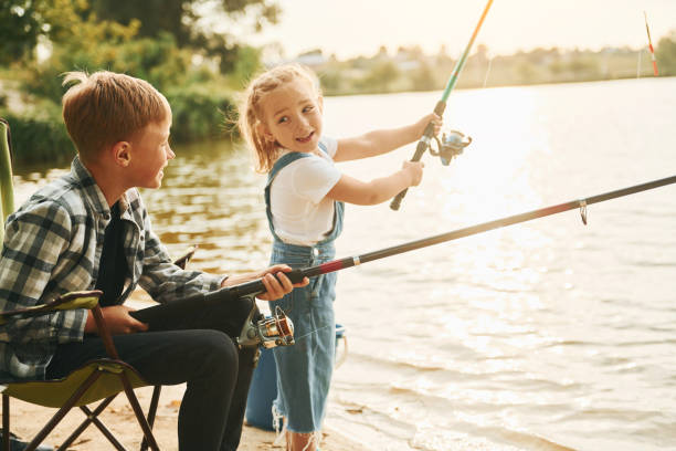 istock Medium sized lake. Boy with his sister in on fishion outdoors at summertime together 1369751148