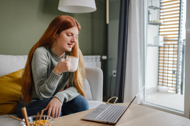 istock Young woman enjoying in the morning coffee while using laptop 1369754254