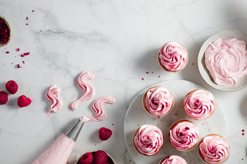 istock Pink cupcakes with a whipped cream cone on table 1369757618
