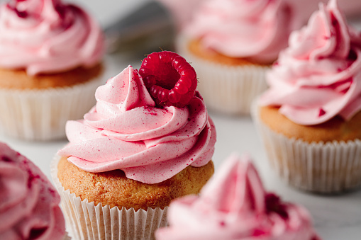Close-up of freshly made raspberry cupcakes. Delicious looking pink cupcakes with raspberry toppings.
