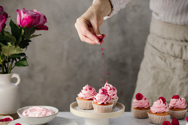 キッチンでラズベリーカップケーキを作る女性 - cupcake sprinkles baking baked ストックフォトと画像