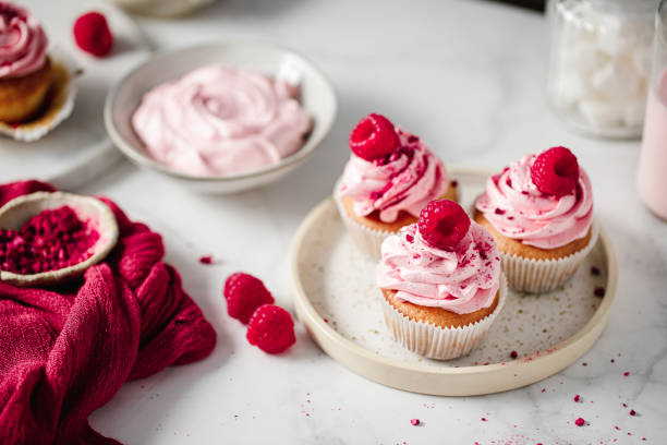 istock Top view of tasty pink cupcakes with raspberry toppings 1369757800