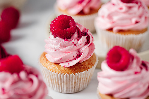 Close-up of delicious pink cupcakes with raspberry toppings. Freshly made raspberry cupcakes.