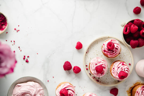 freshly prepared raspberry cupcakes on kitchen counter - cupcake cake sweet food dessert imagens e fotografias de stock