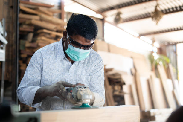 istock Focsu on carpenter, Indian carpenter with medical face mask protective eyeglasses working on wood polishing at workplace - concept of safety measures and covid-19 coronavirus protection during pandemic. 1369759671