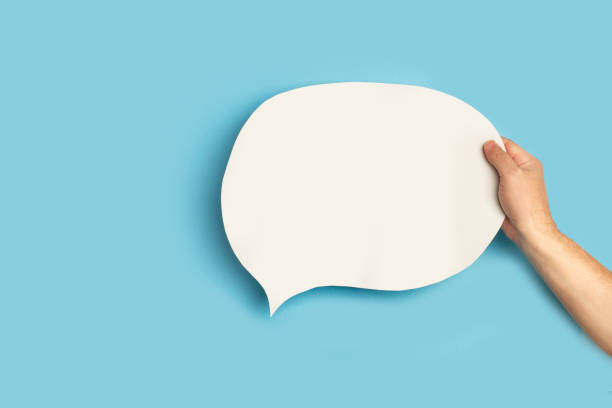 istock Man hand holding a blank white chat bubble on a blue background 1369762528