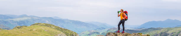 istock Woman hiker drinking water on mountain overlooking view panorama 1369762600