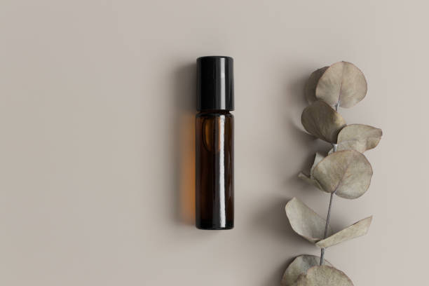 Amber glass roll-on bottle mockup with an eucalyptus on the beige background.