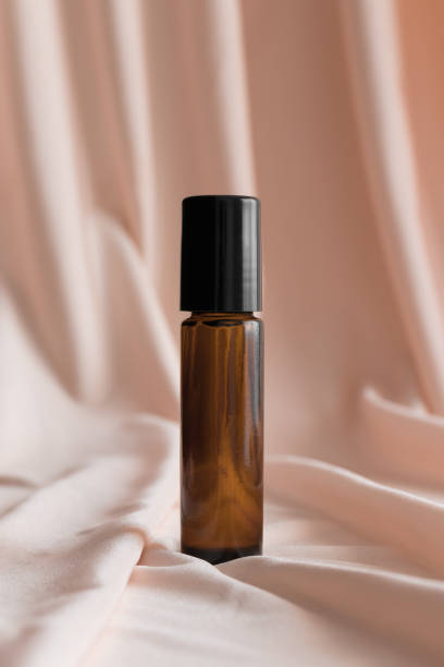 istock Amber glass roll-on bottle mockup on the soft pink textile. 1369763695