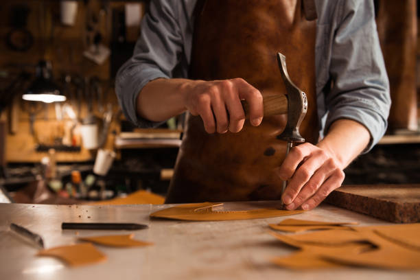 istock Close up of a shoemaker man working with leather using crafting tools 1369766040