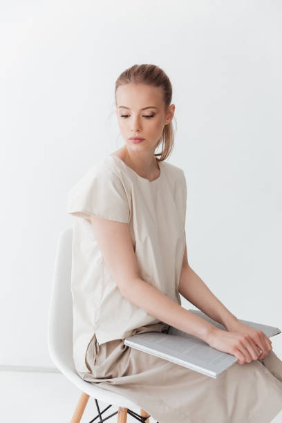 istock Concentrated blonde lady sitting indoors reading book. 1369768774