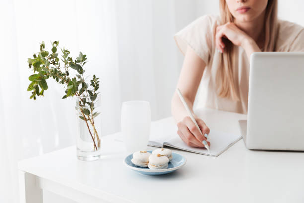 istock Cropped image of blonde woman using laptop writing notes. 1369769139