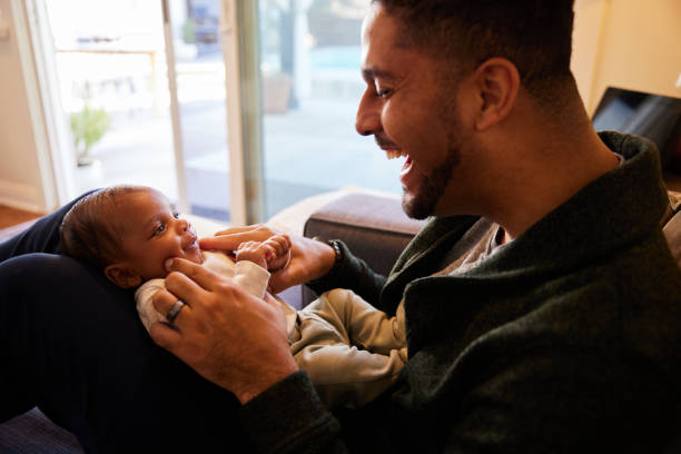 istock Laughing dad playing with his little baby boy lying on his lap 1369770234