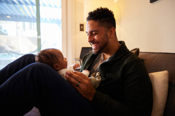 istock Father smiling down at his adorable baby boy lying on his lap 1369770268