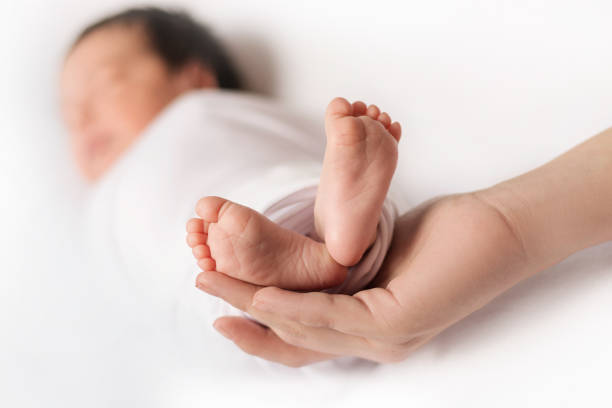istock women's hand hold the baby's legs. 1369772151