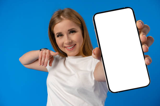 istock Young woman point finger at isolated smartphone screen over blue color background 1369772221