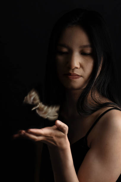 istock Asian woman with flying moth over her hands 1369772504