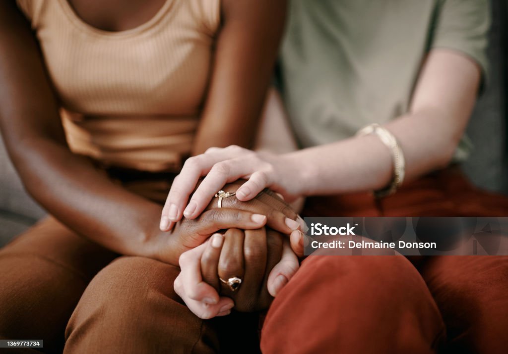 Shot of two friends holding hands supporting one another Our bond is ocean deep Consoling Stock Photo