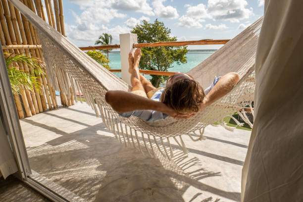 молодой человек отдыхает в гамаке на балконе - beach tourist resort mexico tropical climate стоковые фото и изображения
